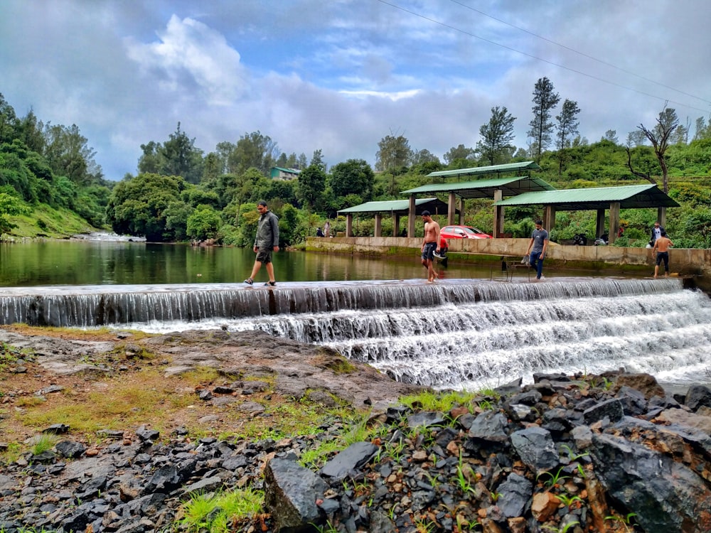 people standing on rock near water falls during daytime