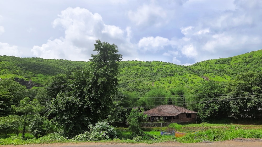 brown wooden house near green trees under white clouds during daytime