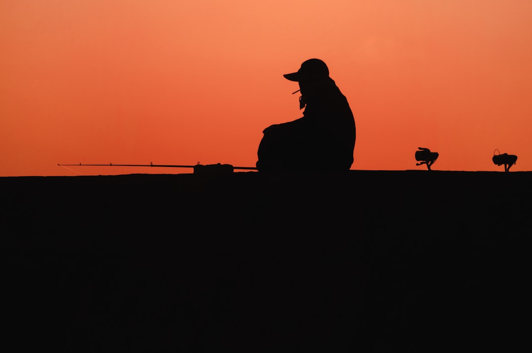 silhouette of person sitting on rock during sunset