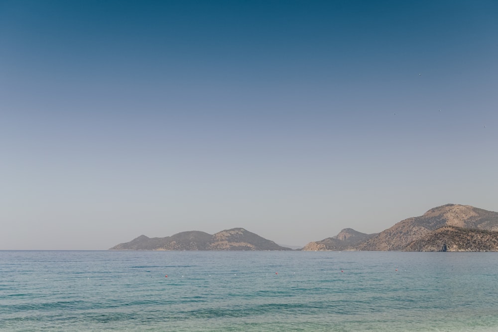 blue sea near mountain under blue sky during daytime