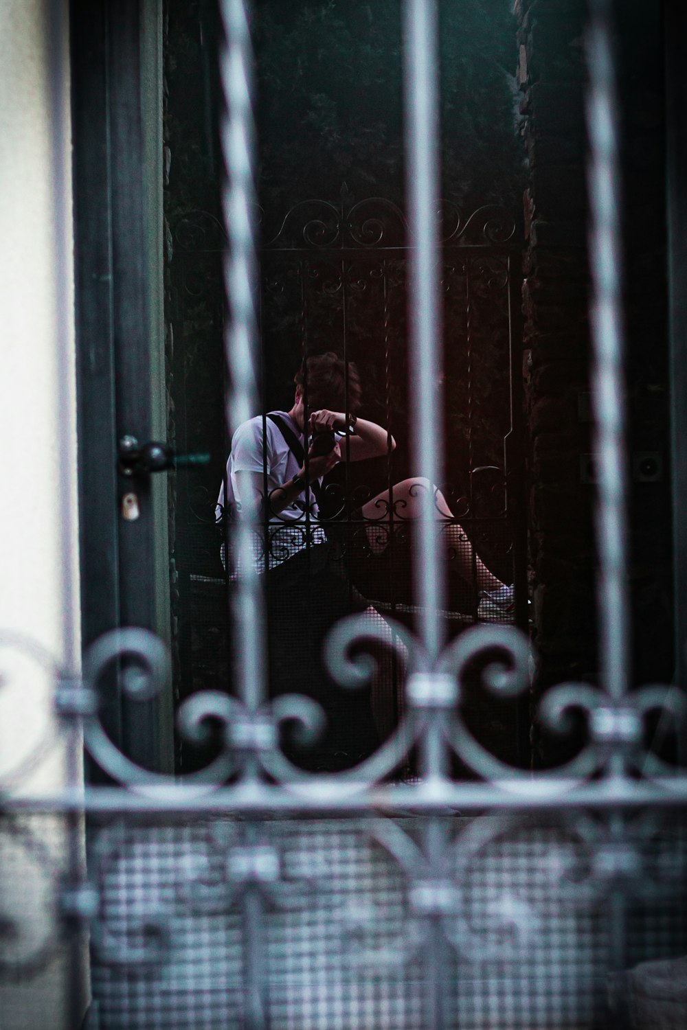 man in white shirt standing in front of black metal gate