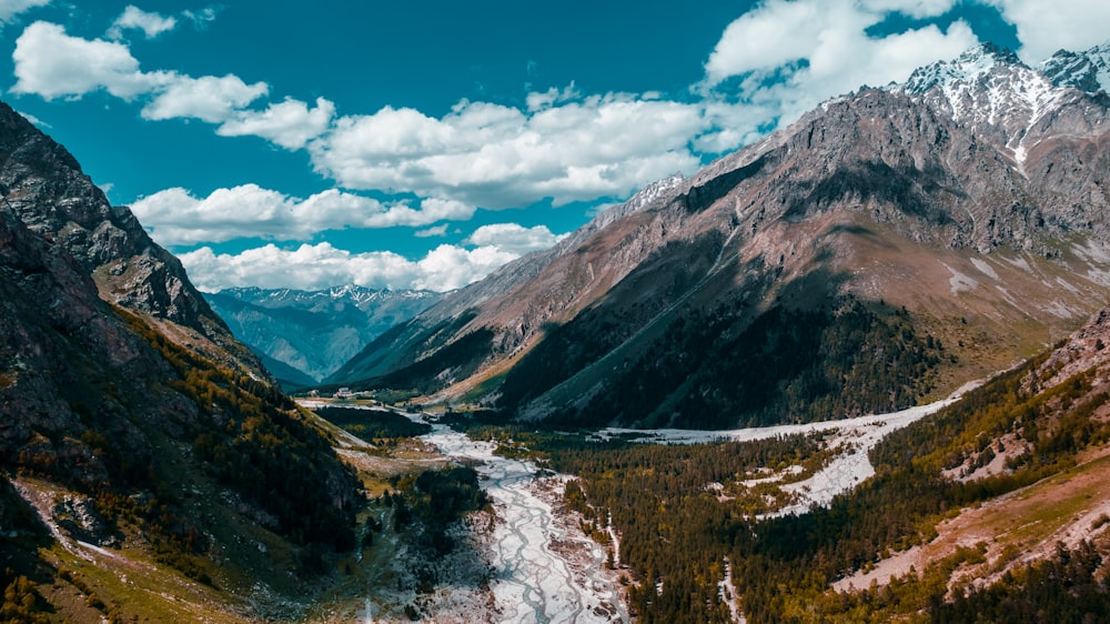 green trees and mountains under blue sky and white clouds during daytime