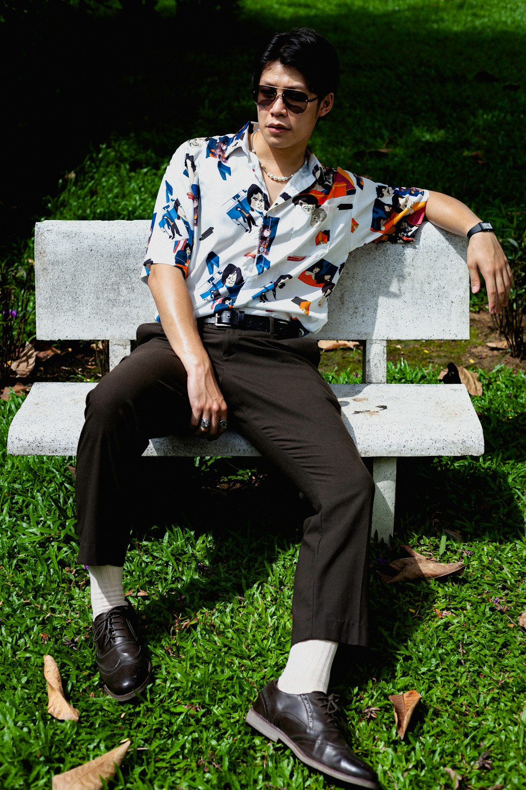 man in white blue and red floral button up shirt and black pants sitting on white