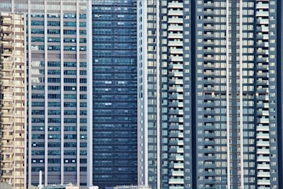 Tall high-rise buildings with numerous glass windows and balconies are tightly packed together, emphasizing urban density. The architecture features modern design elements with vertical lines and repetitive patterns.