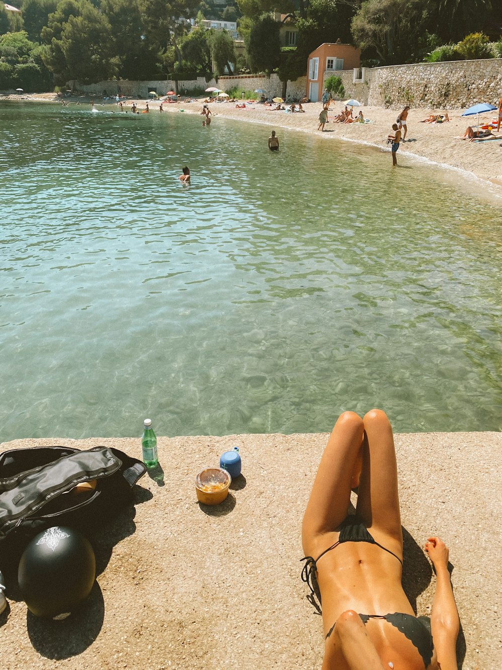 woman in black bikini lying on beach sand during daytime