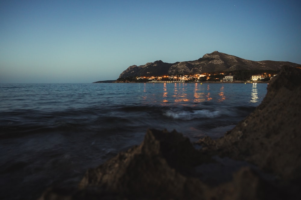 body of water near mountain during night time