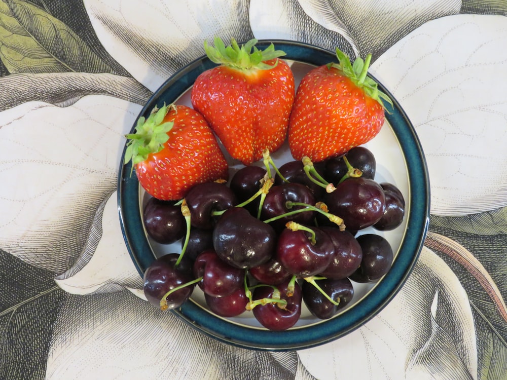 strawberries and grapes on blue ceramic bowl