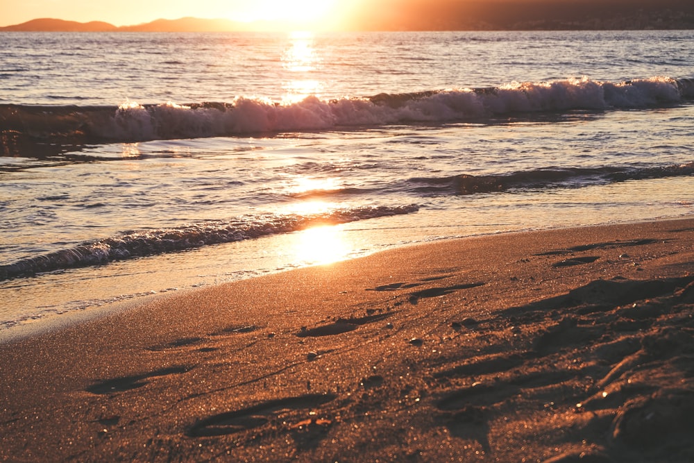 sea waves crashing on shore during sunset