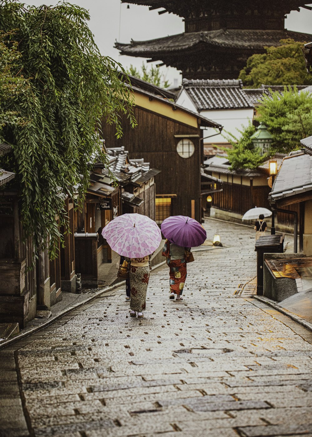 昼間に歩道を歩くピンクの傘をさした女性