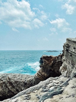 gray rocky mountain beside blue sea under blue sky during daytime