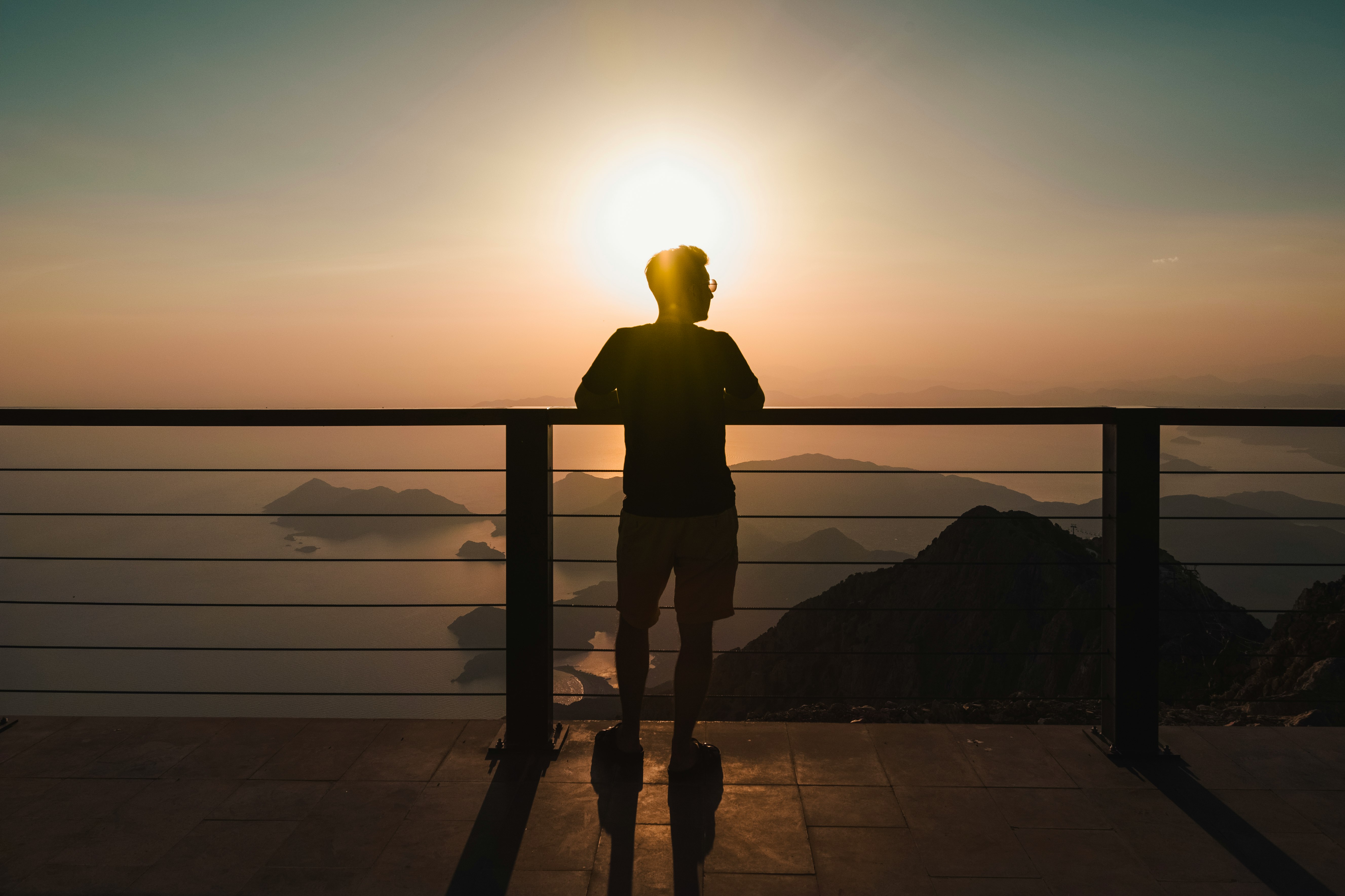 silhouette of person standing on dock during sunset