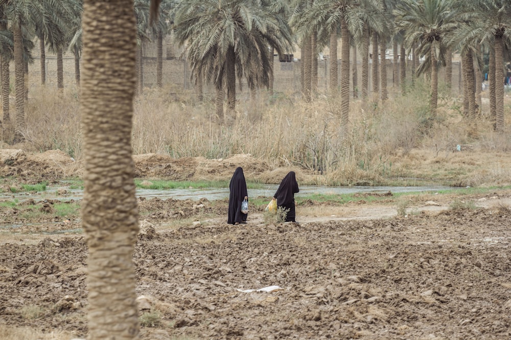 man in black robe walking on brown dirt road during daytime