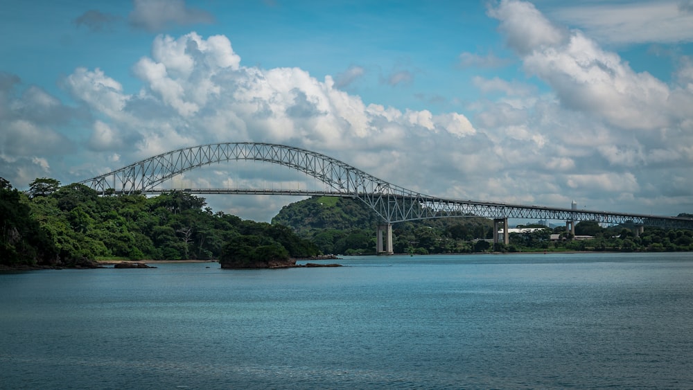 gray metal bridge over blue sea under blue sky and white clouds during daytime