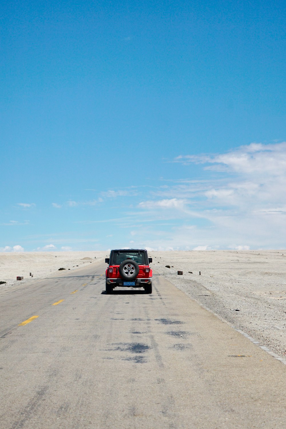 red and black suv on gray asphalt road under blue sky during daytime