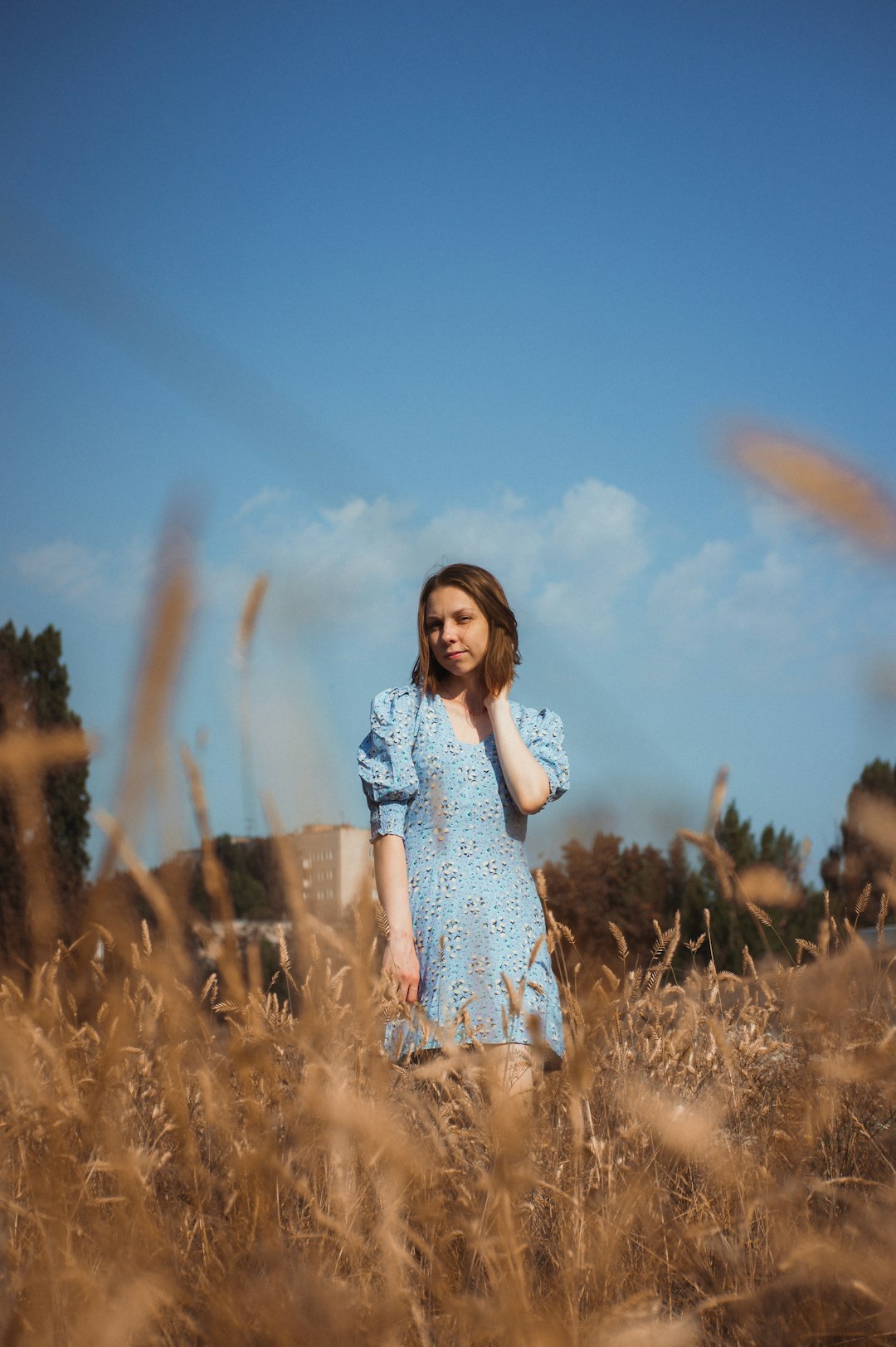 girl in white and blue floral dress standing on brown grass field during daytime