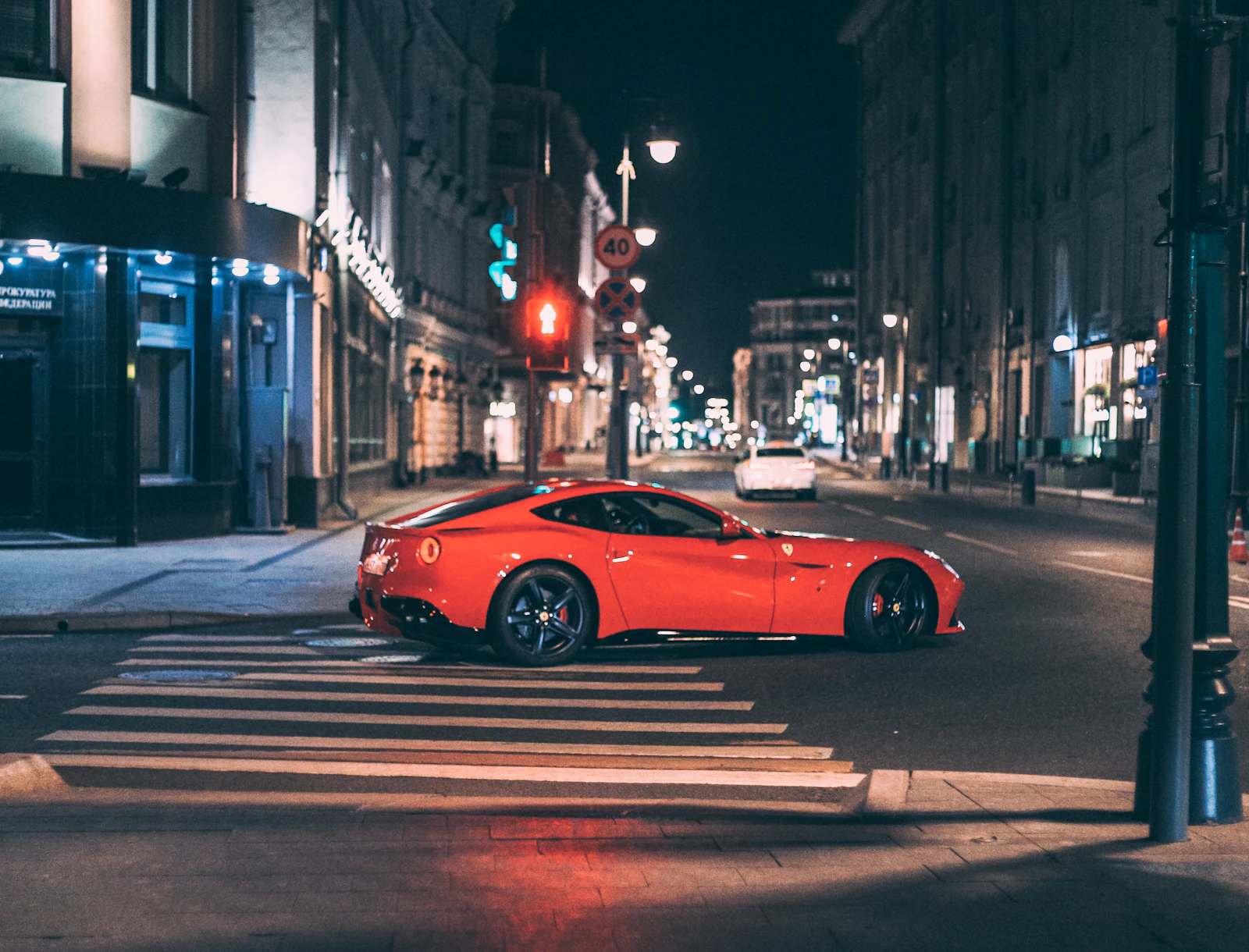 Red Ferrari crossing a city street at night