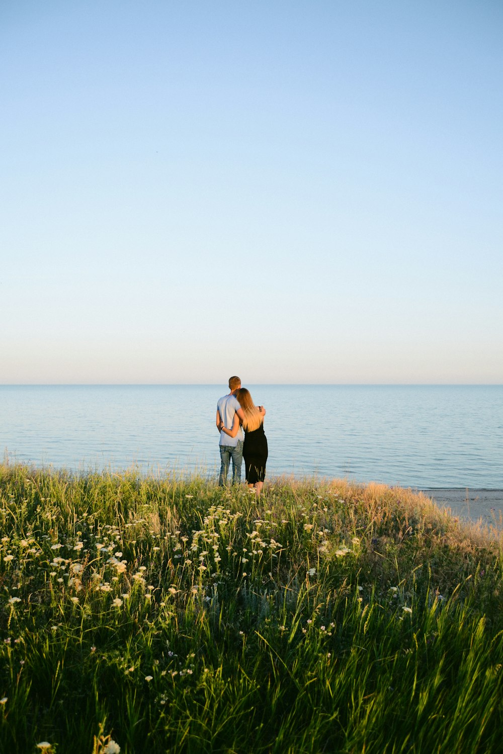 woman in black tank top and black pants standing on green grass field near body of near on near on