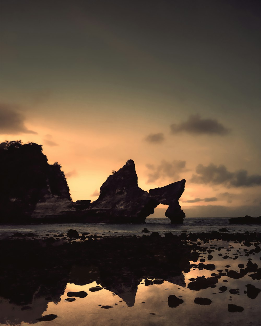 silhouette of rock formation on sea shore during sunset