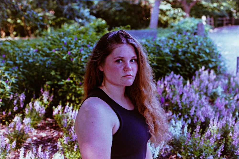 woman in black tank top standing near green plants during daytime