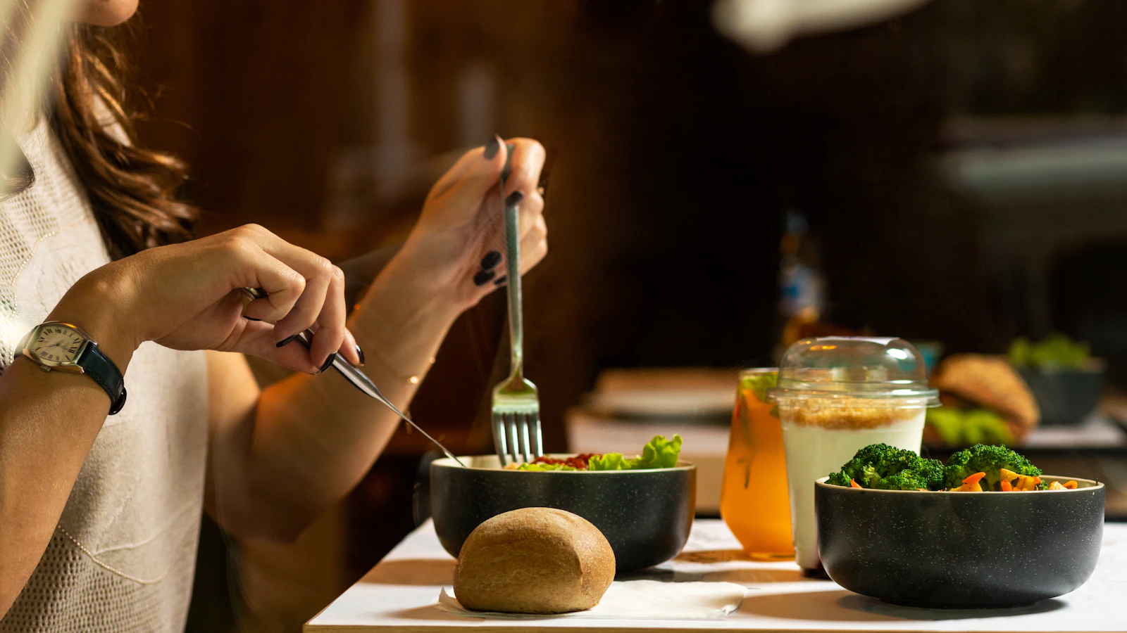 A woman enjoying a fresh salad with fruit and vegetables at the table.