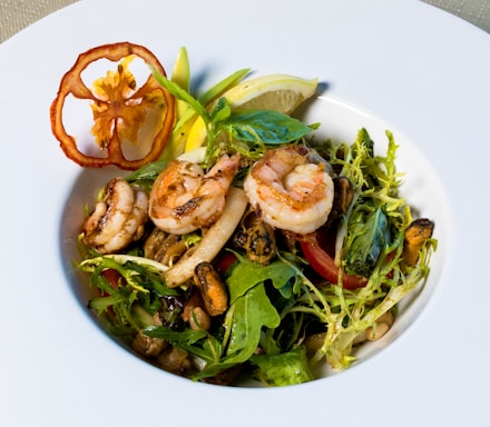 A vibrant plate of grilled shrimp garnished with fresh herbs and lemon wedges.