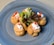 A plate with five puff pastries arranged in a circular pattern around a small bunch of fresh mixed greens. The pastries are topped with a dollop of cream and garnished with small orange roe.