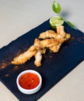 Golden fish-free prawns served with a tangy dipping sauce on a rustic ceramic plate.