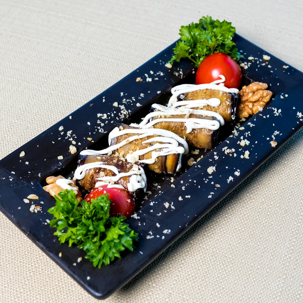 brown bread with white cream and green vegetable on black rectangular tray