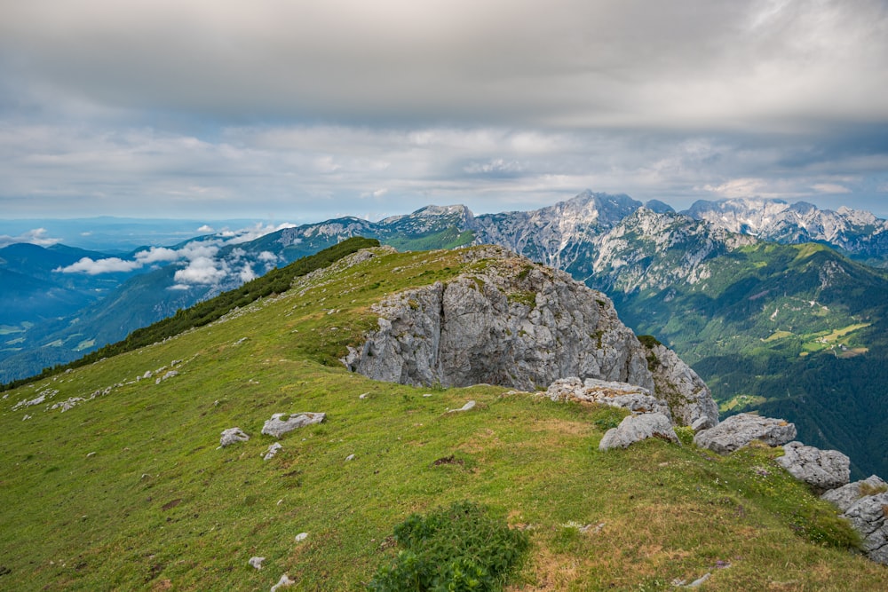 green grass field and gray rocky mountain under blue sky during daytime