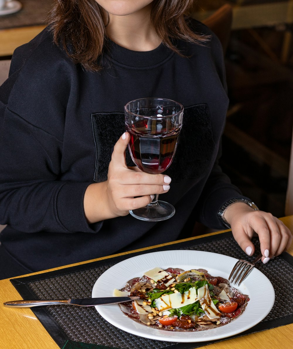 Frau in schwarzem Langarmhemd mit klarem Trinkglas