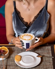 woman in blue sleeveless dress holding white ceramic mug