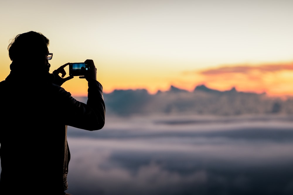 person holding black dslr camera during sunset