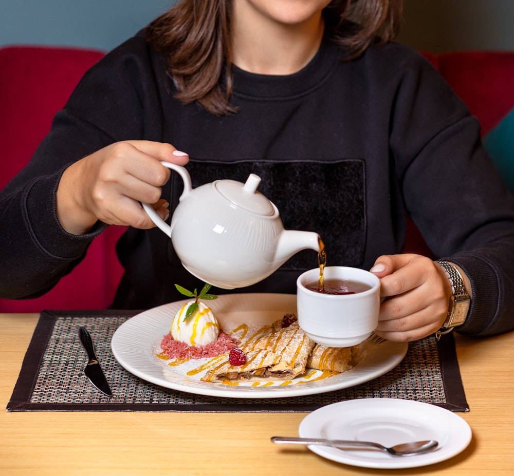 woman in black long sleeve shirt holding white ceramic teapot