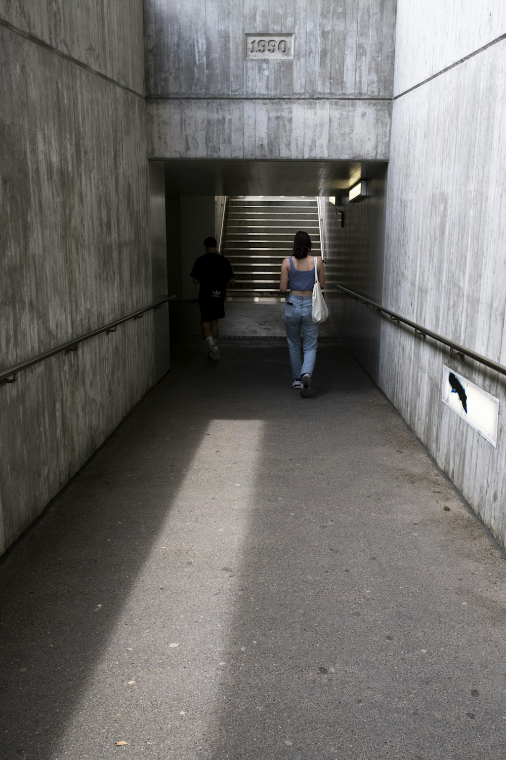 man in blue t-shirt and blue denim jeans walking on hallway