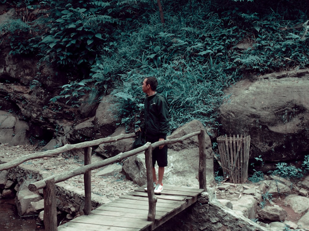 man in black jacket and black pants standing on brown wooden stairs