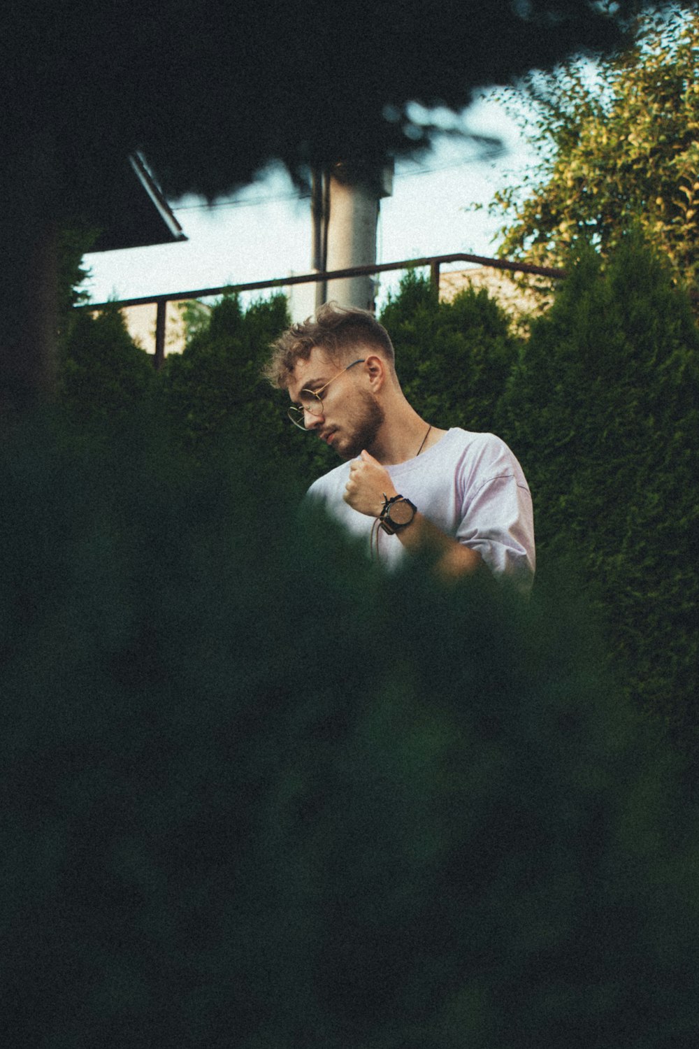 man in white crew neck t-shirt standing near green trees during daytime