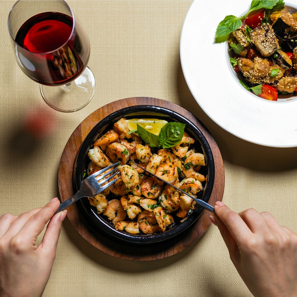 person holding black ceramic bowl with food