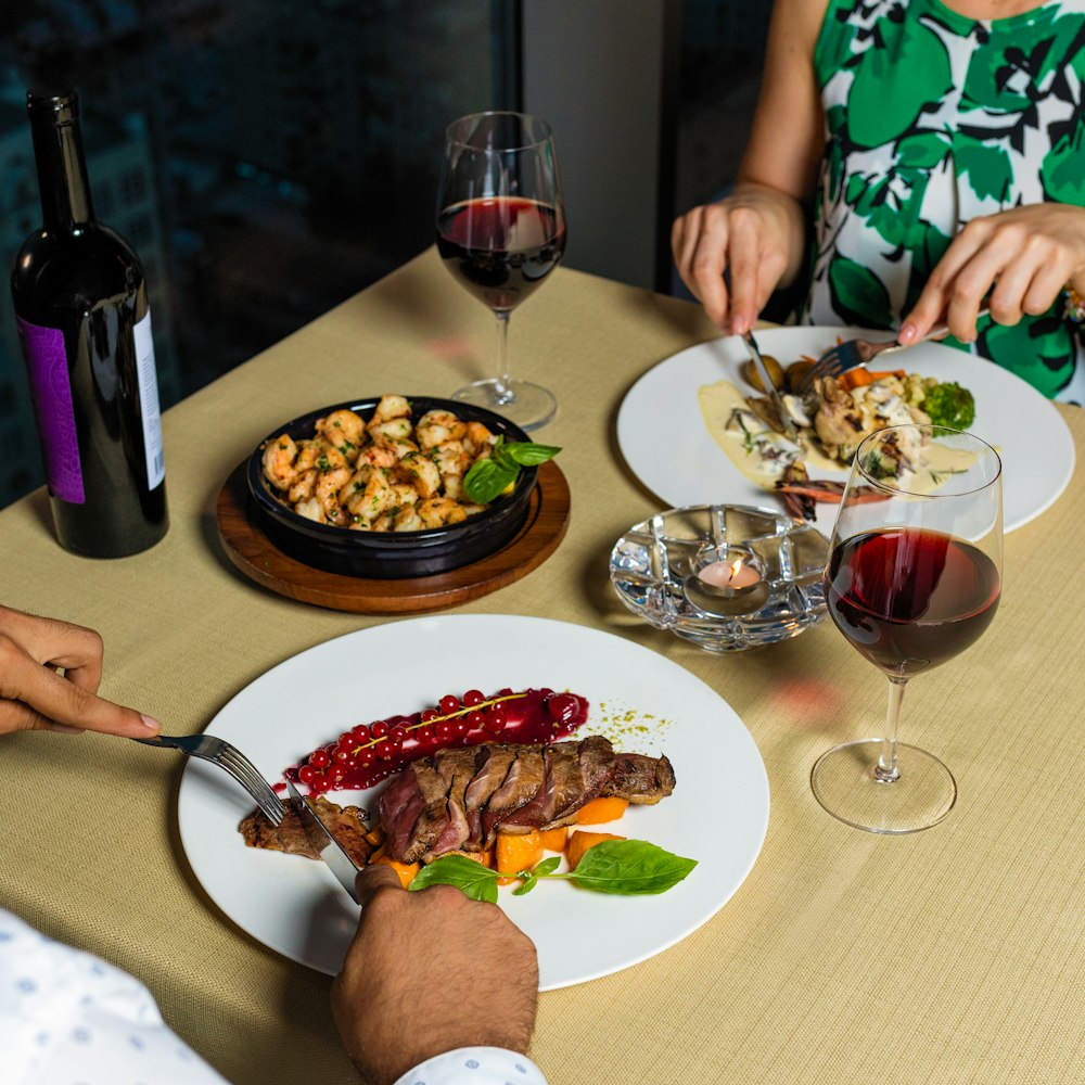 person in green and white floral shirt sitting beside table with food