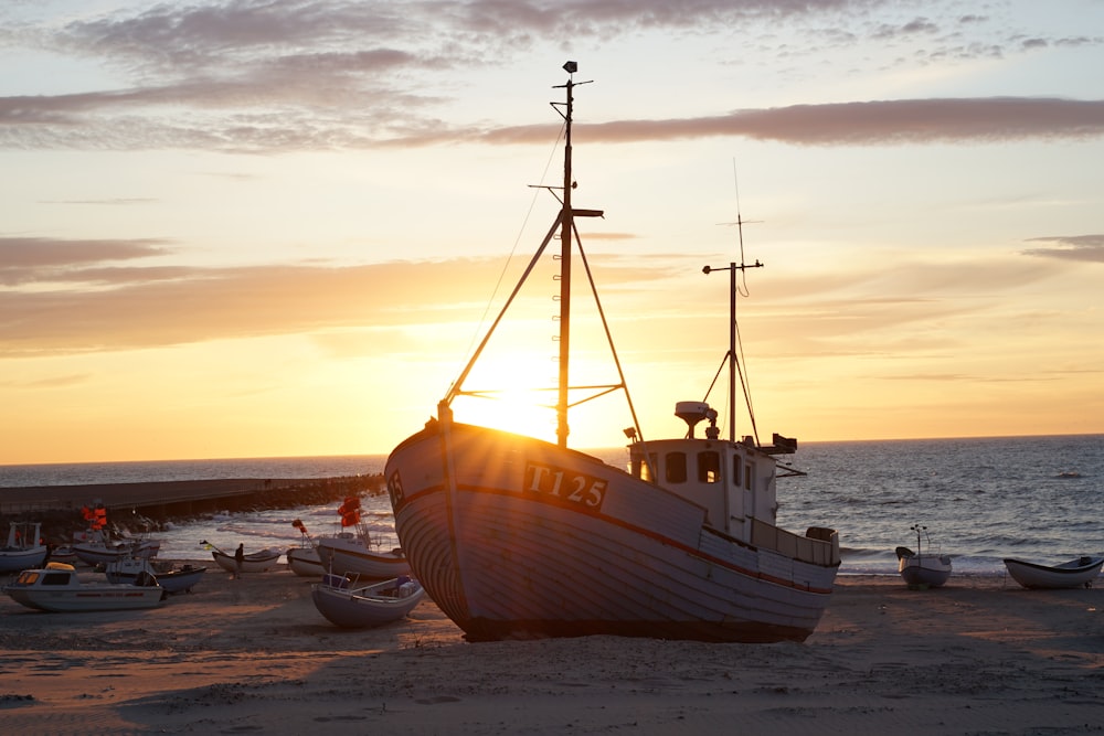 white and brown boat on beach during sunset