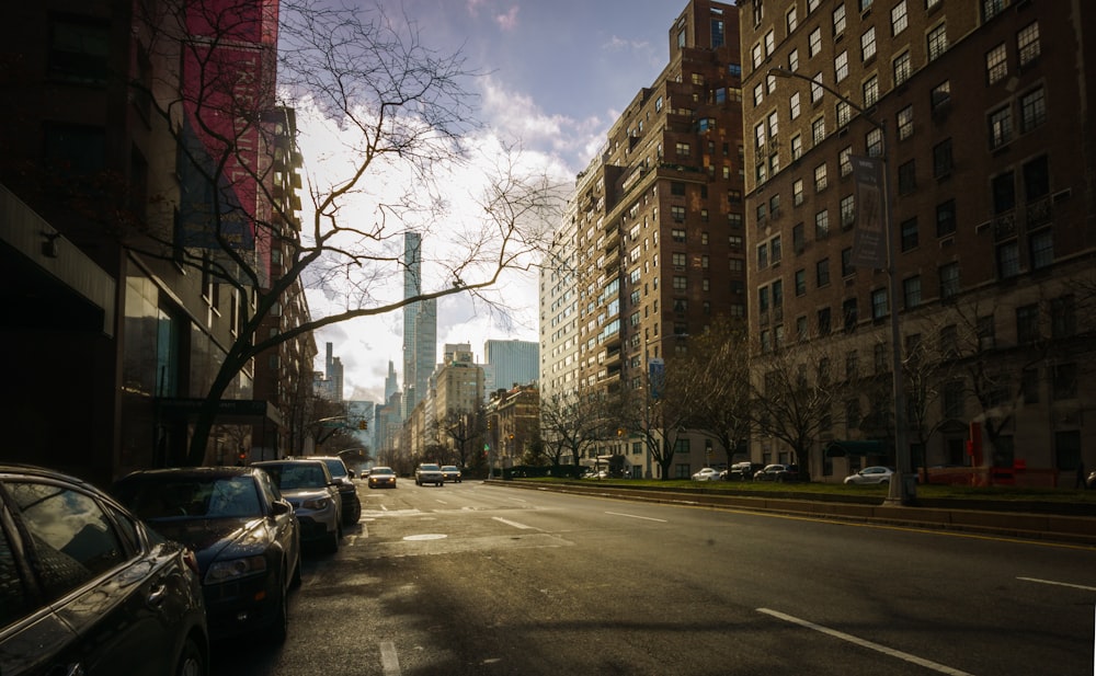 cars parked on side of the road near high rise buildings during daytime