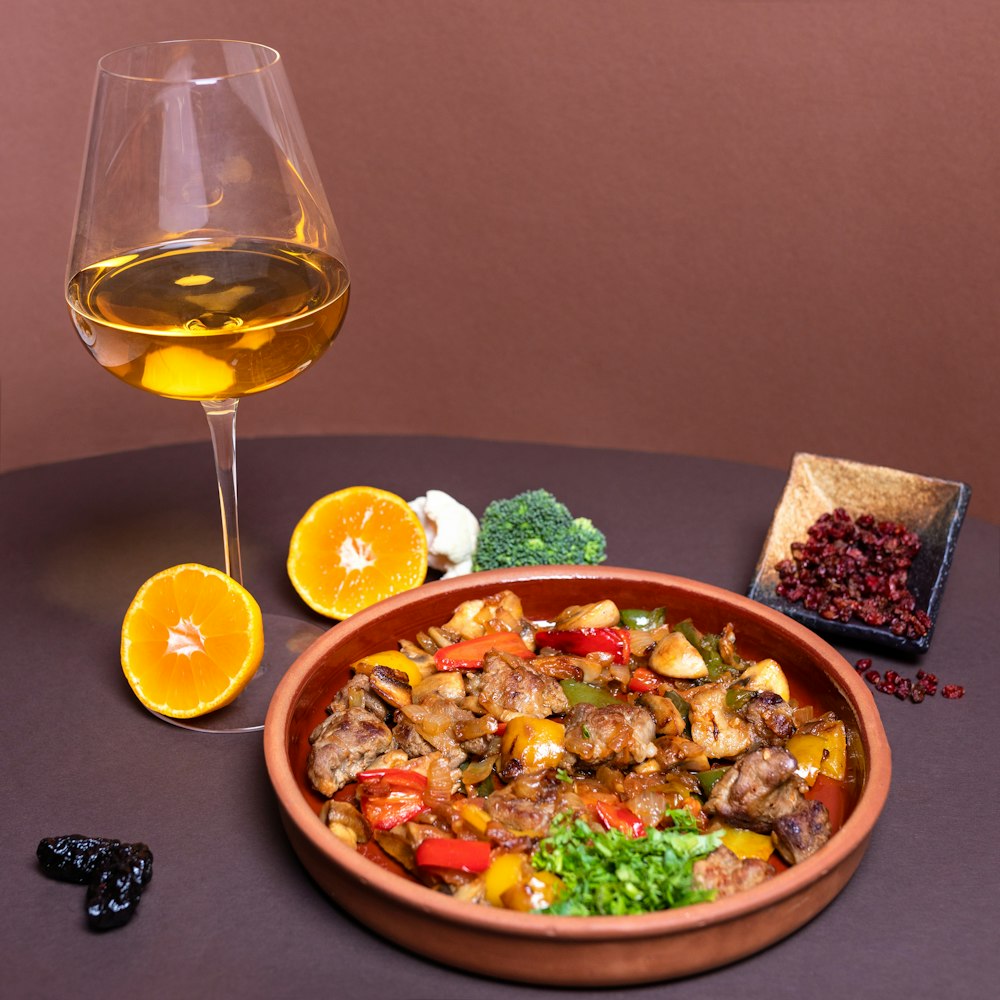 vegetable salad on brown ceramic bowl beside clear wine glass