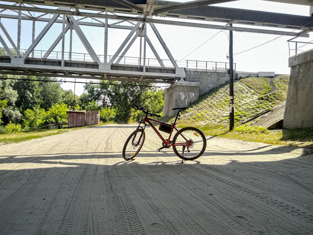 Bicicleta roja y negra en carretera de asfalto gris durante el día