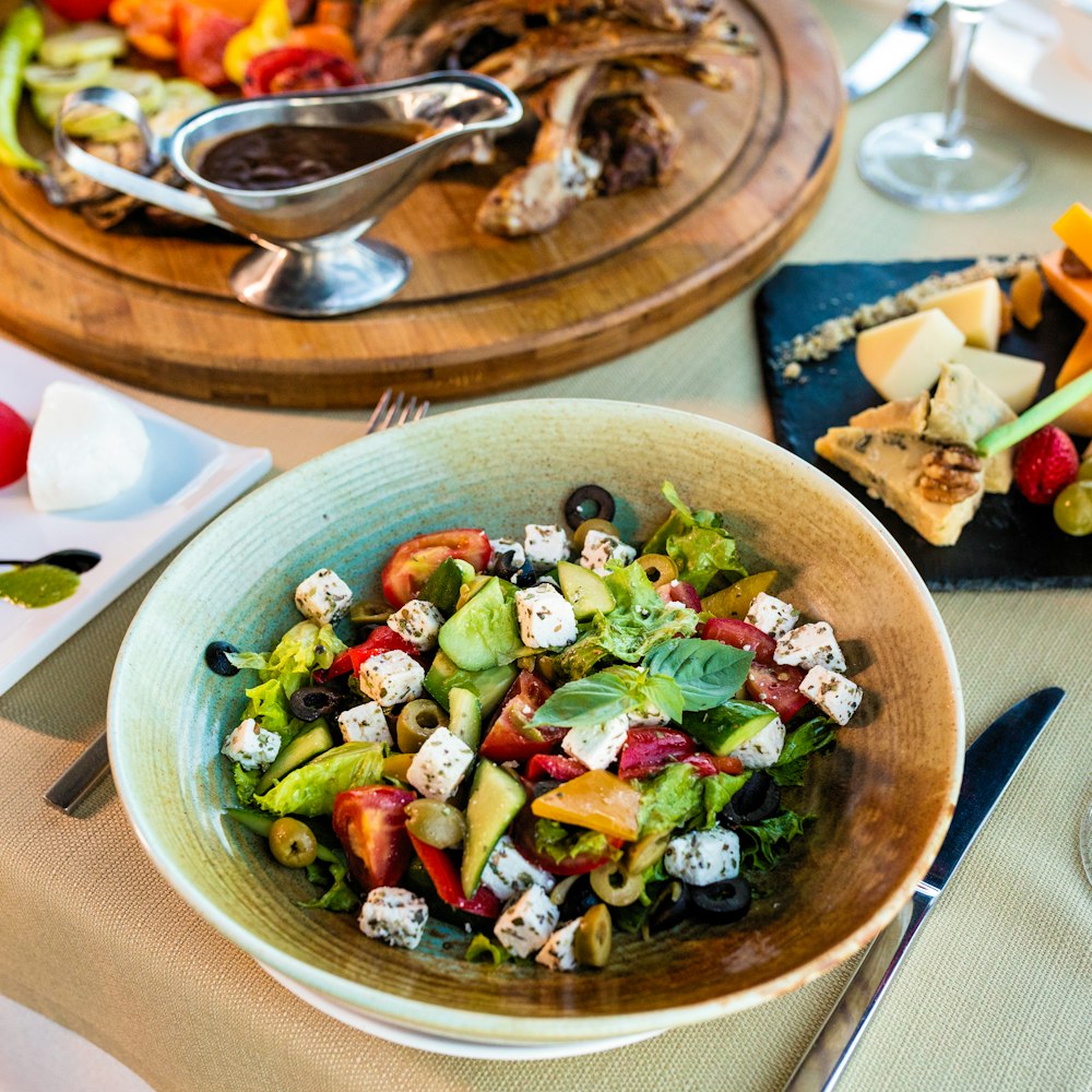 Griekse salde met feta, olijven en tomaat op een tafel met ander eten 