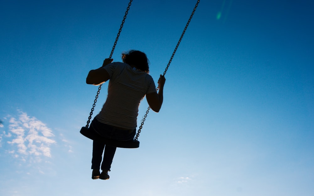 boy in black and white striped shirt sitting on swing during daytime