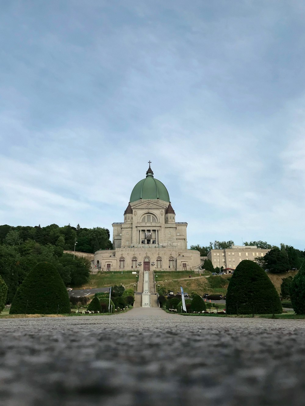 bâtiment en béton blanc et brun près d’arbres verts sous des nuages blancs pendant la journée