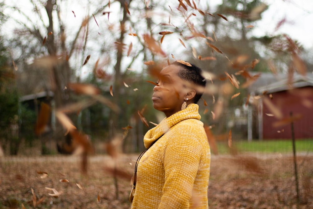 woman in yellow knit sweater standing near brown trees during daytime