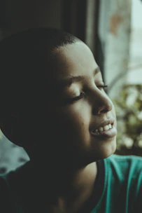 A calm moment of a young child meditating with eyes closed, surrounded by soft natural light.