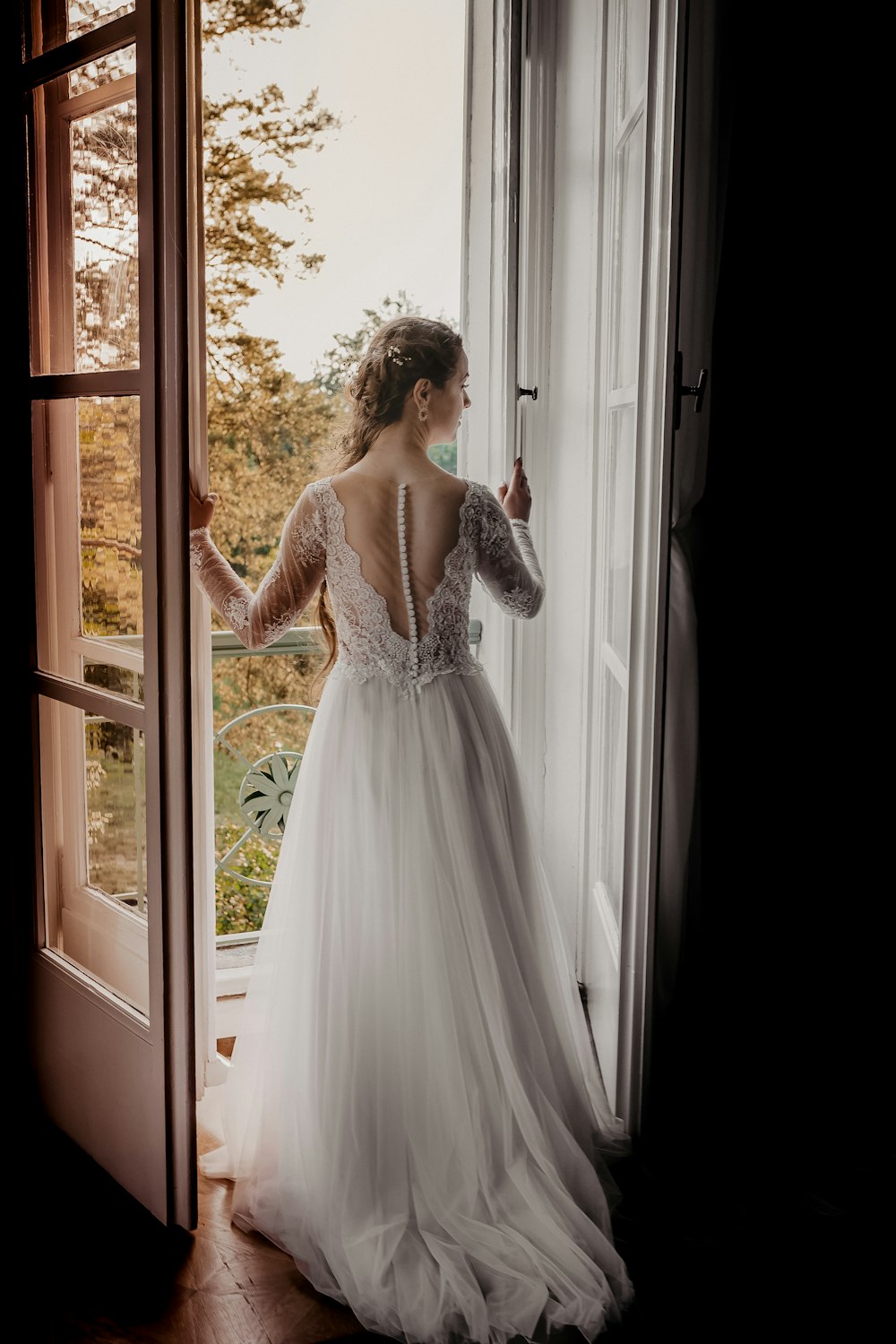 woman in white floral dress standing beside window during daytime