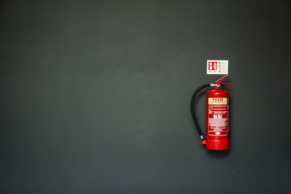 extintor de incendios rojo en la pared gris