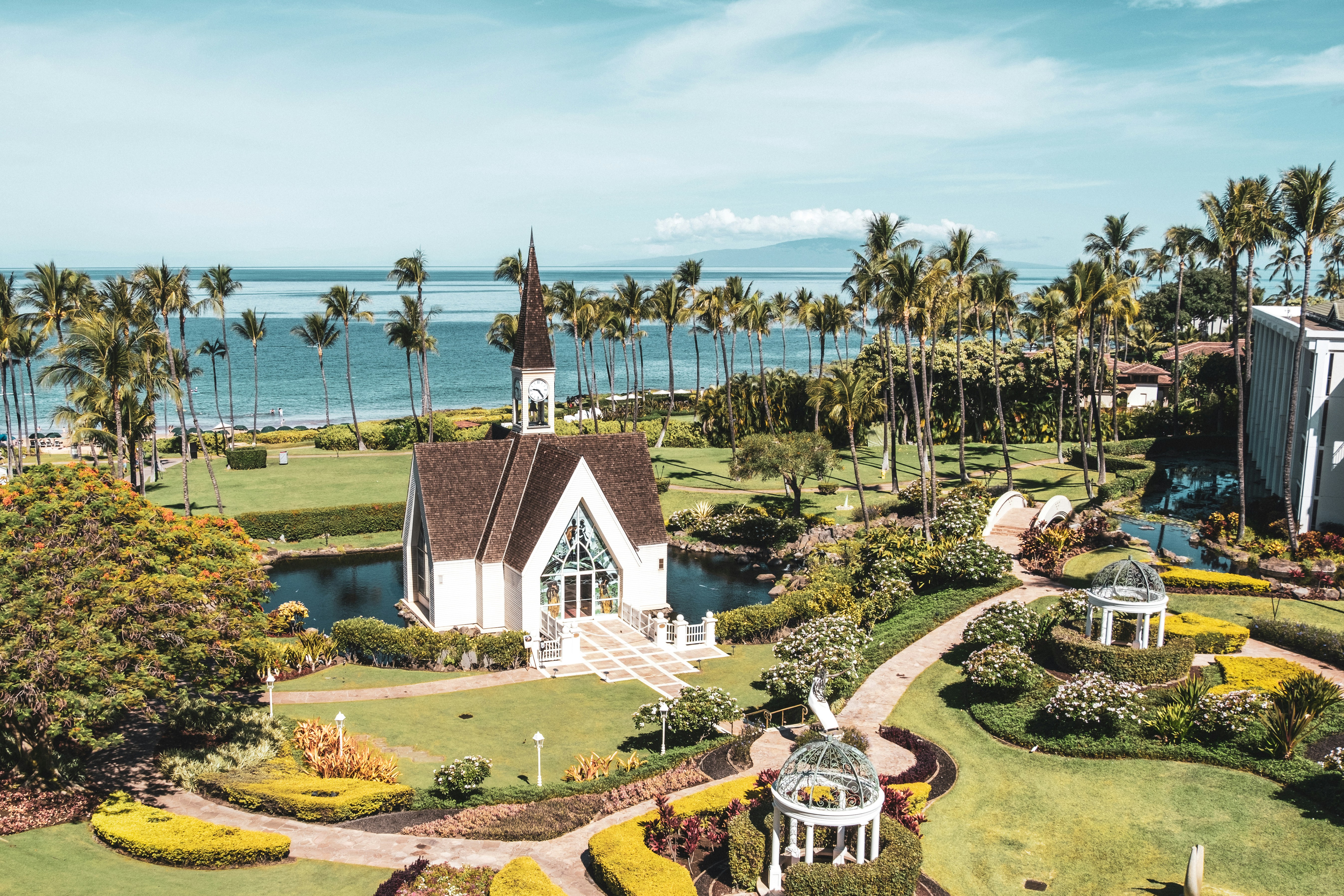 white and brown concrete house near green trees and body of water during daytime, 